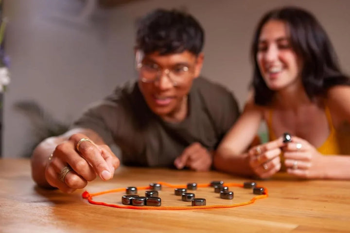 Teens and adults playing tabletop magnetic puzzle game