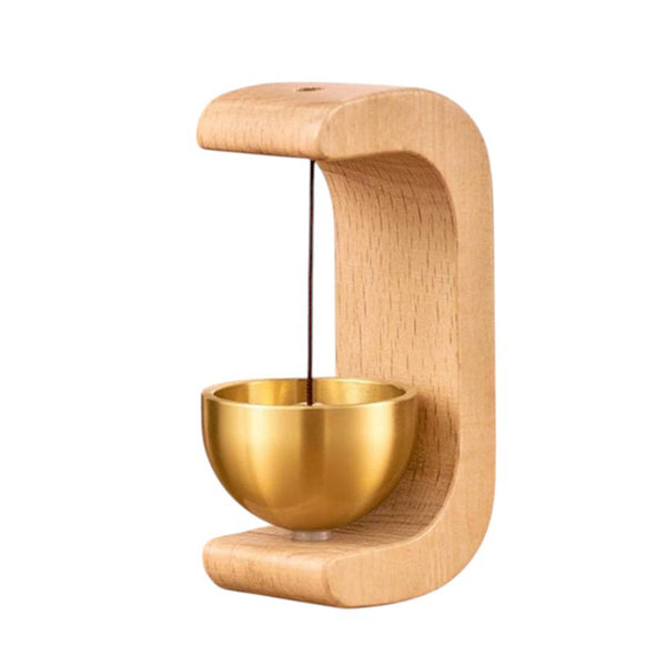 Beech wood and brass door chime on wooden table in sunlight
