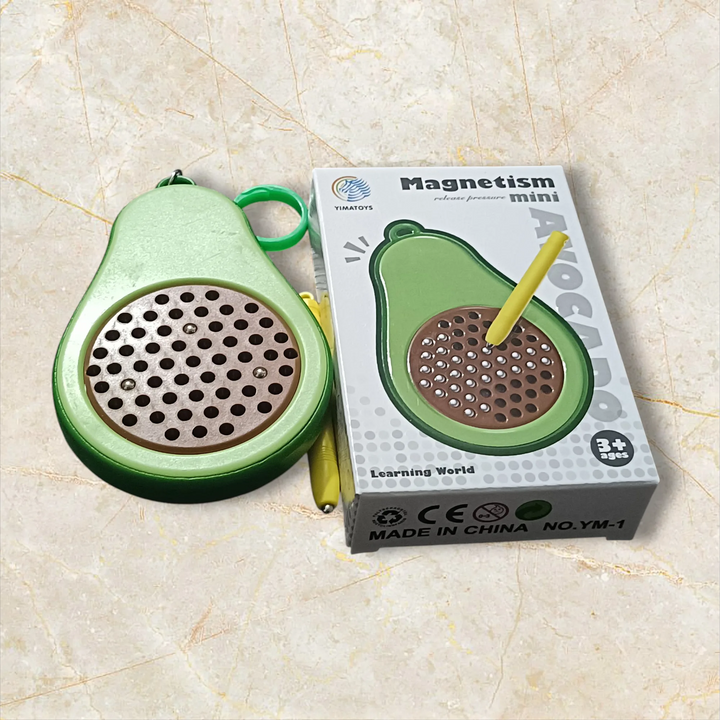 Green avocado-shaped educational toy with perforated surface and yellow stick, next to its packaging on a beige marble background.  Vaayu-E-Store, vaayu, Vayu Magnatic Toys ,Games