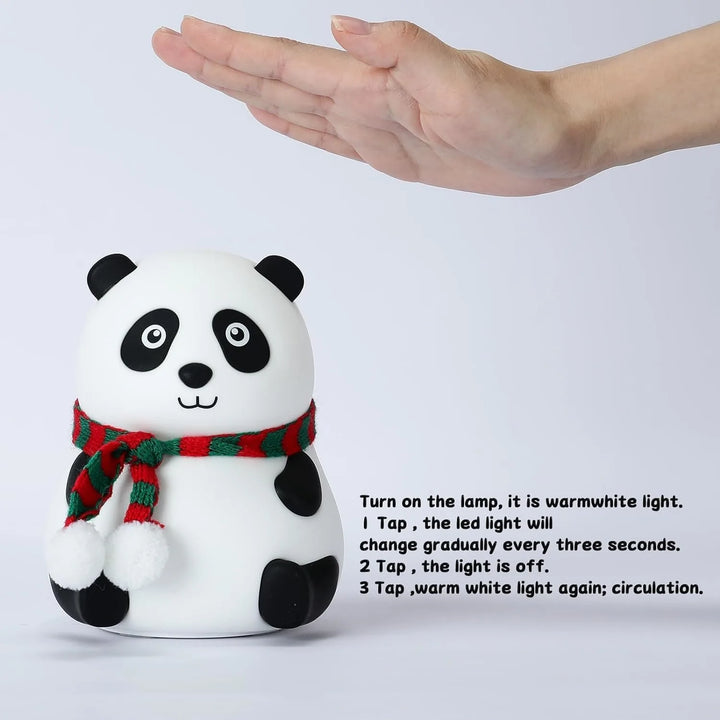 Panda-shaped night light with a red and green scarf, held by a hand against a white background.